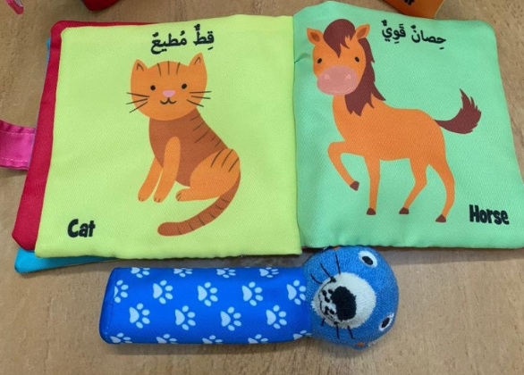 كتاب قماشي للأطفال يحتوي على صور حيوانات كوأسمائها باللغتين العربية والإنجليزية. يحتوي الكتاب على شريط إغلاق  وجيب جانبي يحمل لعبة قماشية مطابقة لإخراجها والضغط عليها لإصدار صوت صرير. المادة مخيطة بإحكام لتحمل الغسيل  الكتاب واللعبة خفيفان الوزن مع حشو ناعم، مما يسهل على الطفل اللعب بهما 